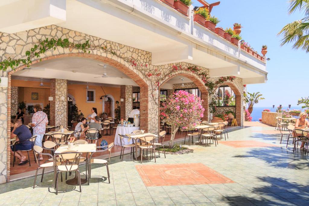 an outdoor patio of a restaurant with tables and chairs at Hotel Olimpo le Terrazze in Letojanni