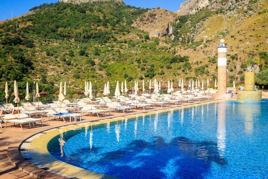 a swimming pool with chairs and a lighthouse at Hotel Olimpo le Terrazze in Letojanni