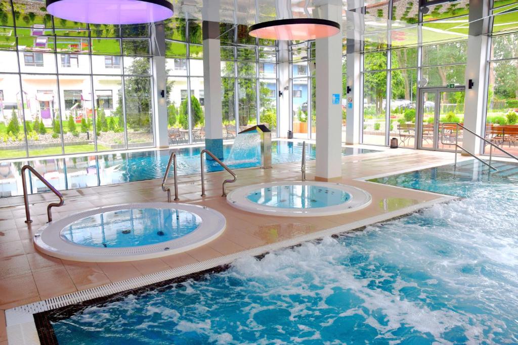 two hot tubs in a large indoor swimming pool at Koral Live in Kołobrzeg