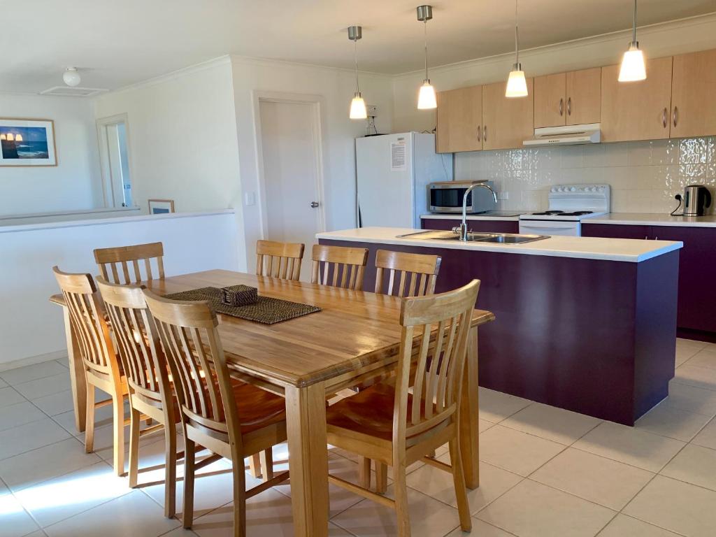 a kitchen with a wooden dining room table and chairs at Bayview Beach House Apartment No 1 in Kingscote