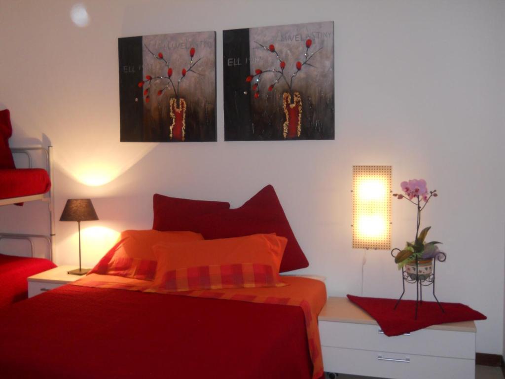 sypialnia z czerwonym łóżkiem i 3 zdjęciami na ścianie w obiekcie B&B Residenza Bianco w mieście Castellana Grotte