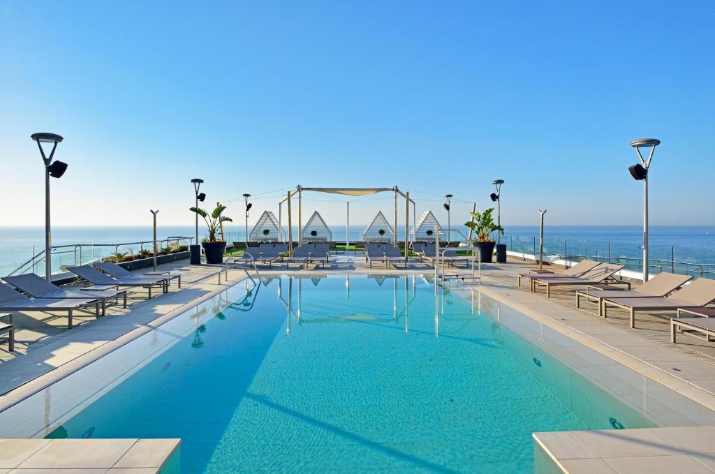 a swimming pool with chairs and the ocean in the background at Melia Costa del Sol in Torremolinos