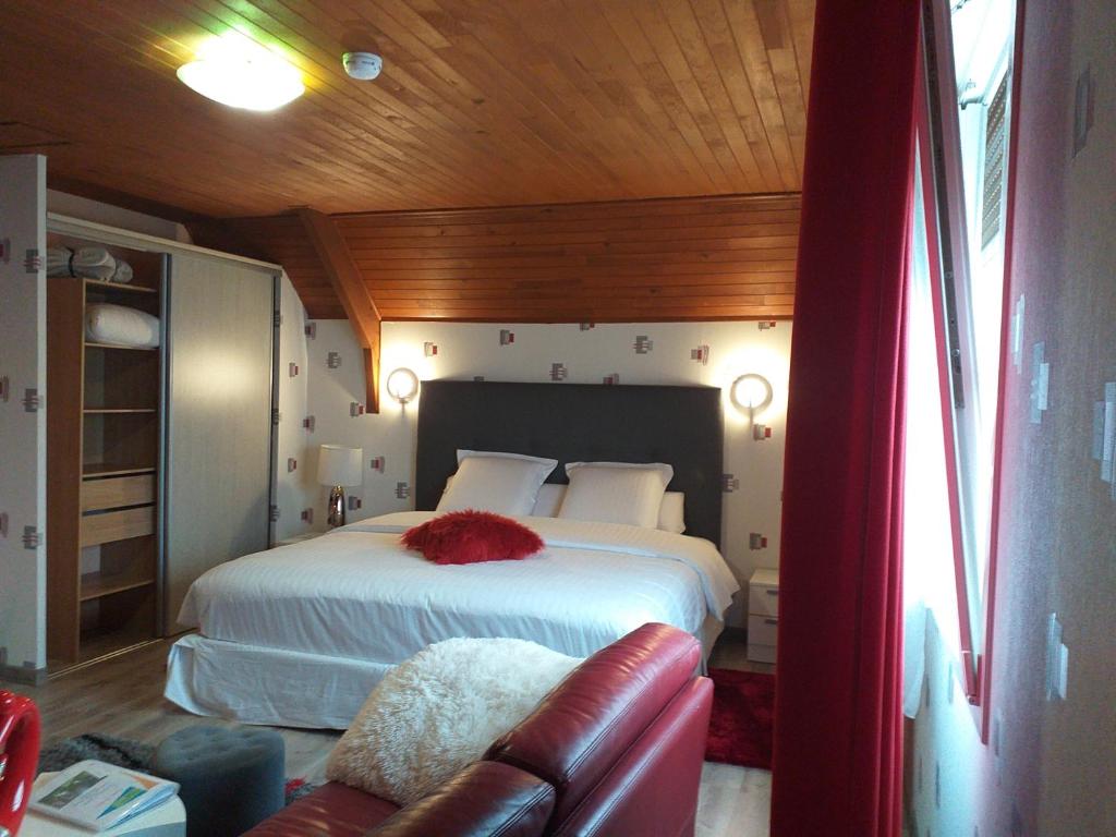 une chambre avec un grand lit et un canapé dans l'établissement Chambres du Jardin Fleuri, à Saint-Aubin-lès-Elbeuf