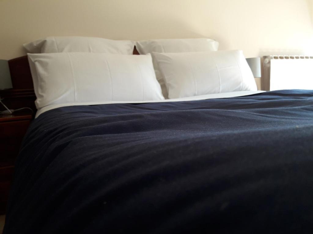 1 cama con almohadas blancas y manta azul en Apartamento céntrico catedral Burgos, en Burgos