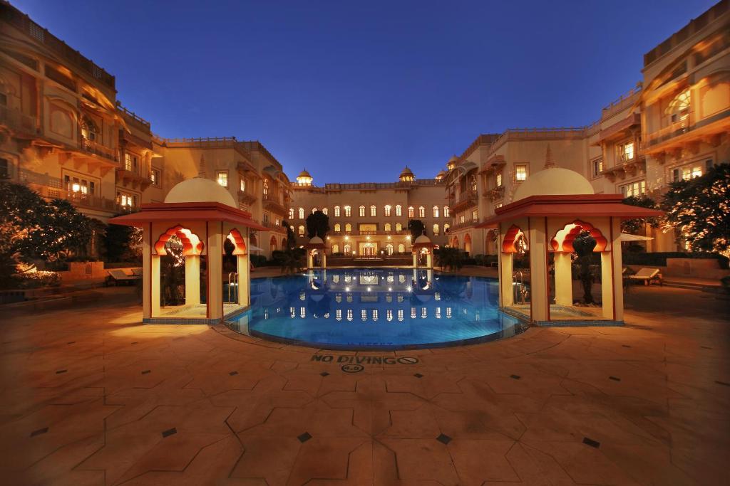 une grande cour avec une piscine ouverte la nuit dans l'établissement Taj Hari Mahal Jodhpur, à Jodhpur