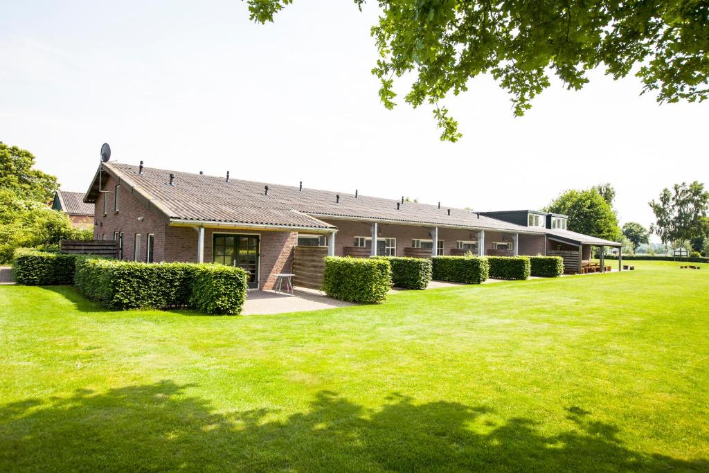 une maison avec une pelouse devant elle dans l'établissement Vakantiehuisjes Op De Horst, à Groesbeek