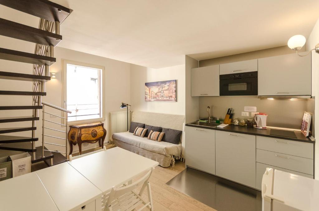 a kitchen with white cabinets and a living room at Appartamento del Nettuno in Bologna
