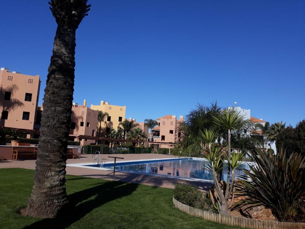 uma piscina num parque com palmeiras e edifícios em RINCON DE SARA em Ayamonte