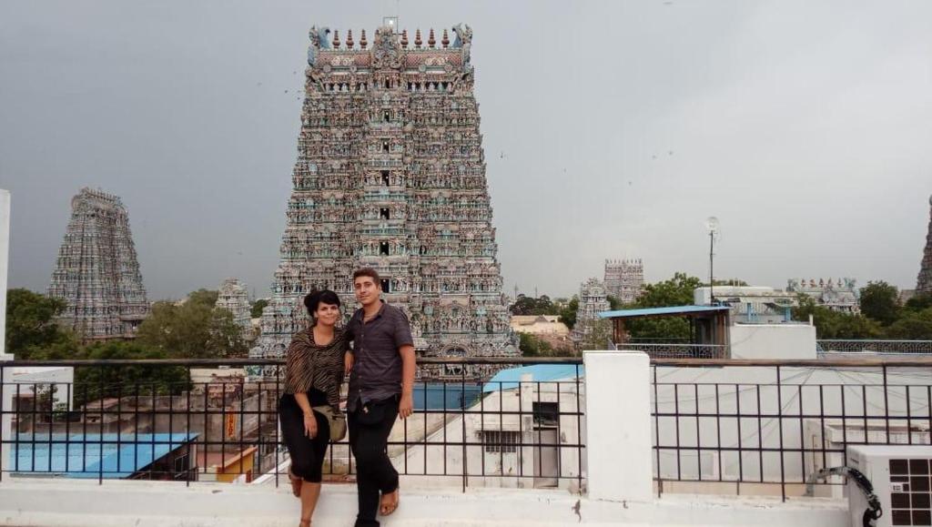 Un uomo e una donna in piedi davanti a un tempio di Hotel Temple View Annex a Madurai