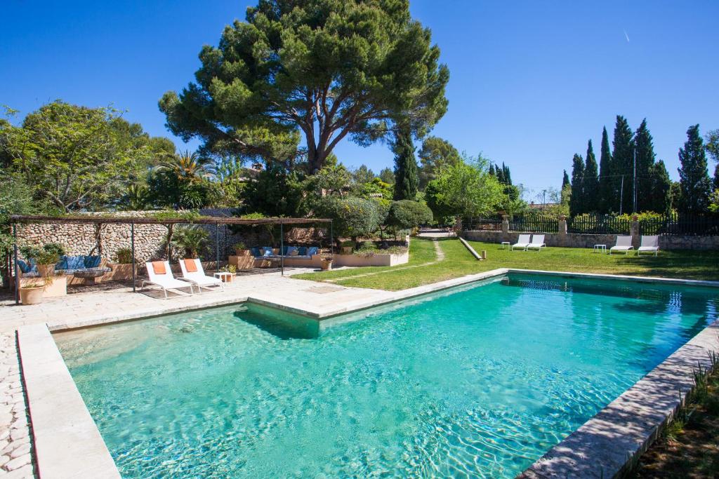 een zwembad in een tuin met stoelen en bomen bij Oliver Moragues Grandhouse & Vineyard in Algaida