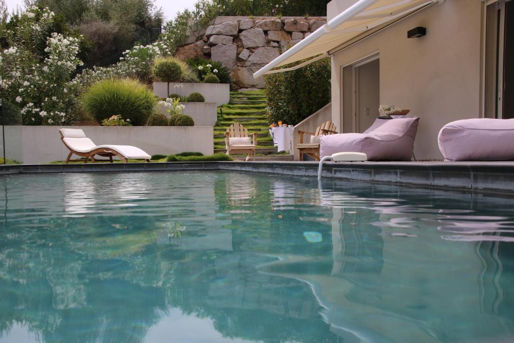 a swimming pool with chairs and a house at VILLA GOLFE AJACCIO près des plages in Ajaccio