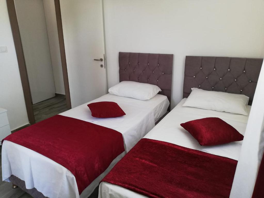 2 bedden met rode kussens in een kamer bij ÇİÇEK APART OTEL in Didim