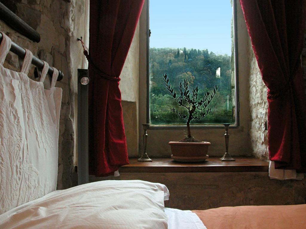 - une chambre avec un lit et une fenêtre avec une plante en pot dans l'établissement La Martellina B&B, à Fiesole
