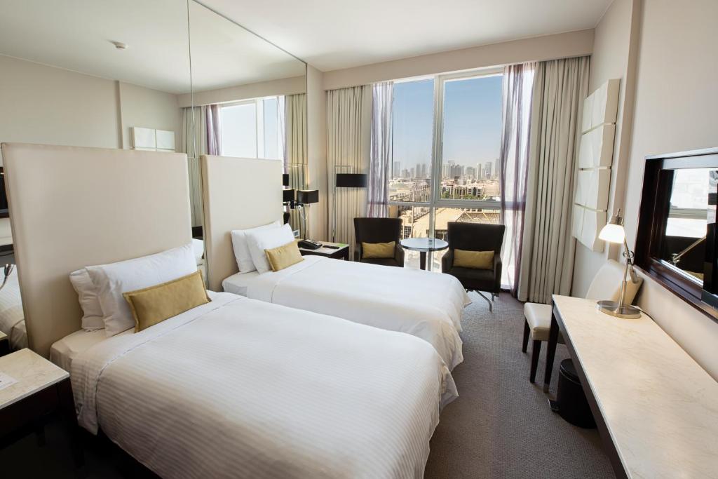 a hotel room with two beds and a television at Centro Al Manhal by Rotana in Abu Dhabi