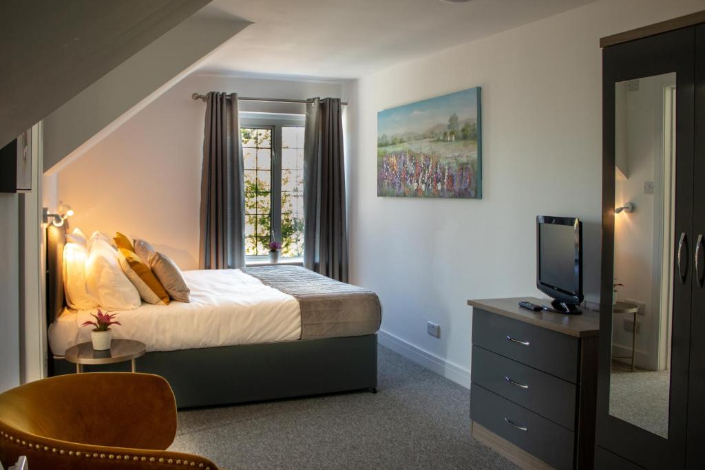 a bedroom with a bed and a tv and a window at Fino Rooms in Felpham