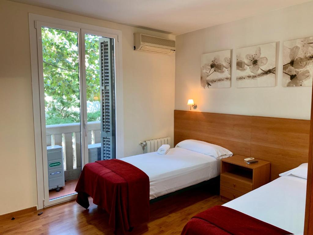 バルセロナにあるオスタル マドラソのベッド2台と窓が備わるホテルルームです。