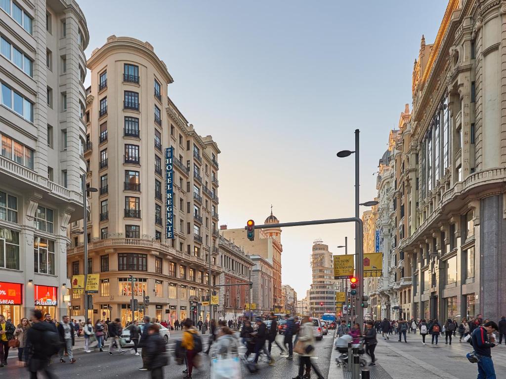 una multitud de personas cruzando una concurrida calle de la ciudad en Regente Hotel en Madrid