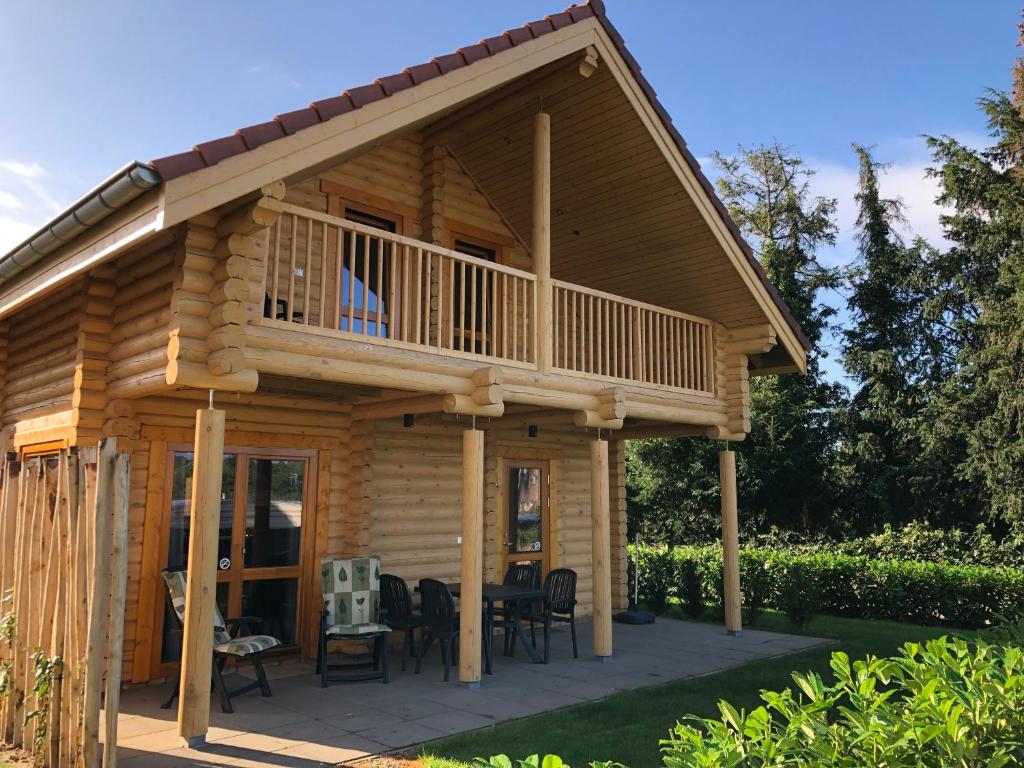 a log cabin with a deck and a table at Boomstamhuis High Chaparral in Oorsbeek