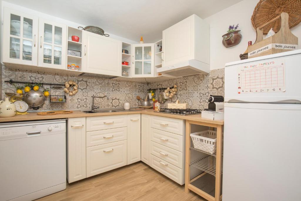 una cucina con armadietti bianchi e frigorifero di Fabiene Familyholidays Gelsonia a Cefalù