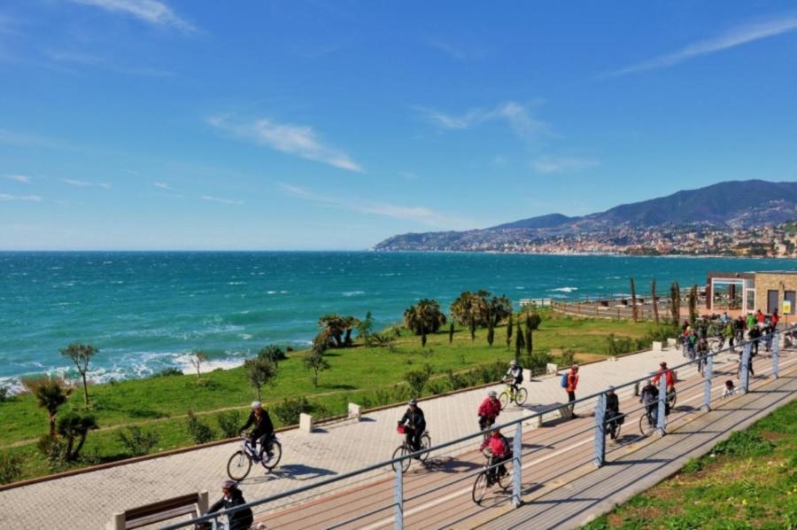 un grupo de personas montando bicicletas por una acera cerca del océano en Gaudio 22 Apartment en San Remo