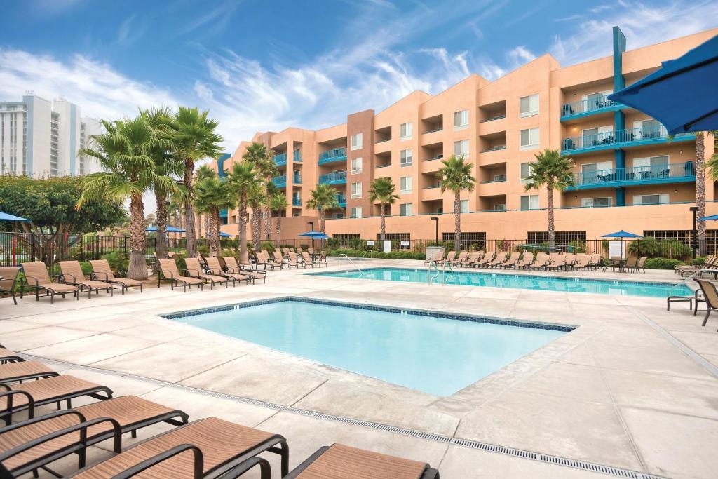 a swimming pool with chairs and a hotel in the background at Worldmark Oceanside Harbor in Oceanside