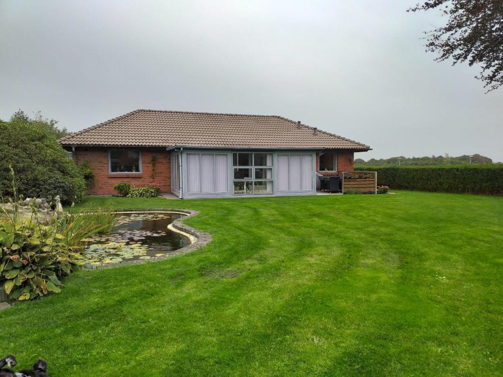 una casa con césped verde y una casa en Villa in Brande en Gammel Blåhøj