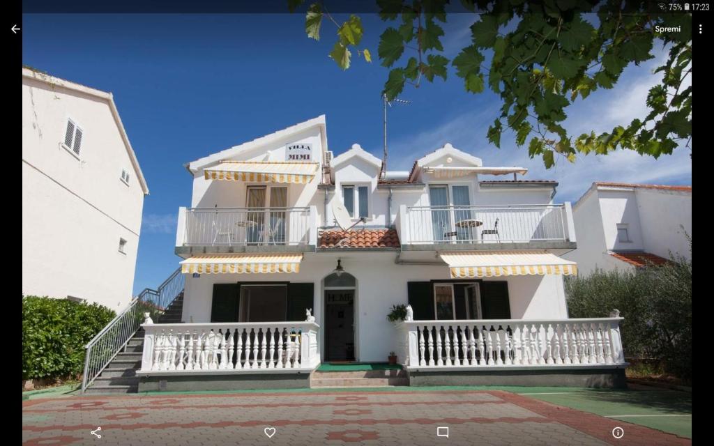 a white house with a white balcony and stairs at Apartmani Villa Mimi in Brodarica