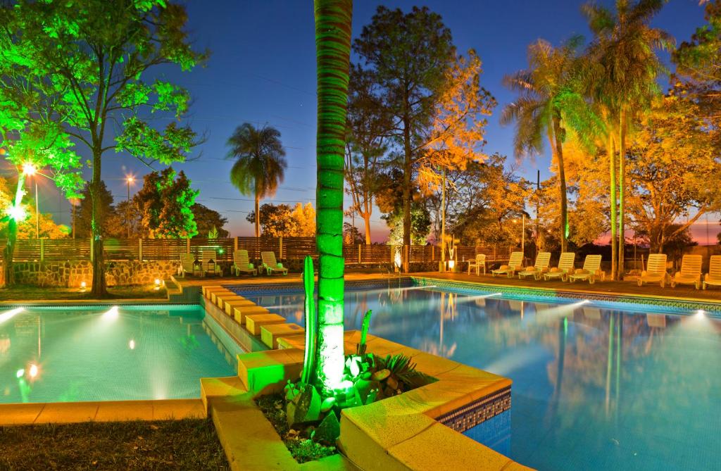 una piscina por la noche con una palmera en el medio en La Mision Posadas en Posadas