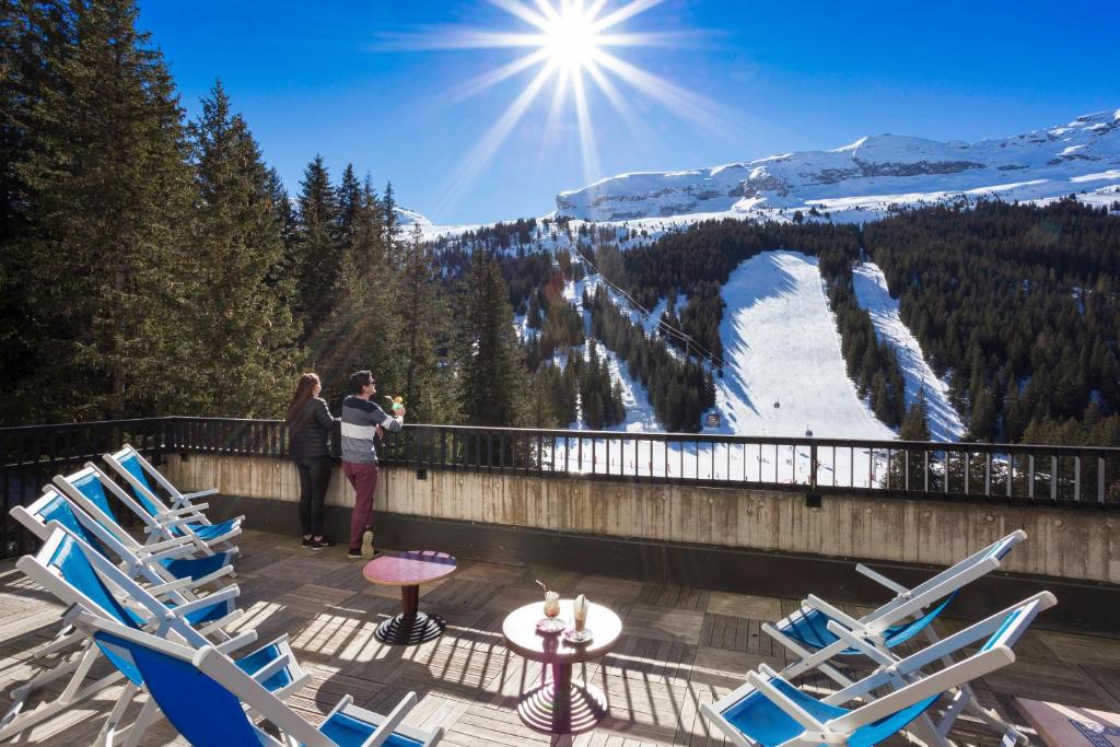 two people standing on a balcony with a view of a mountain at Hôtel Club mmv Le Flaine *** in Flaine