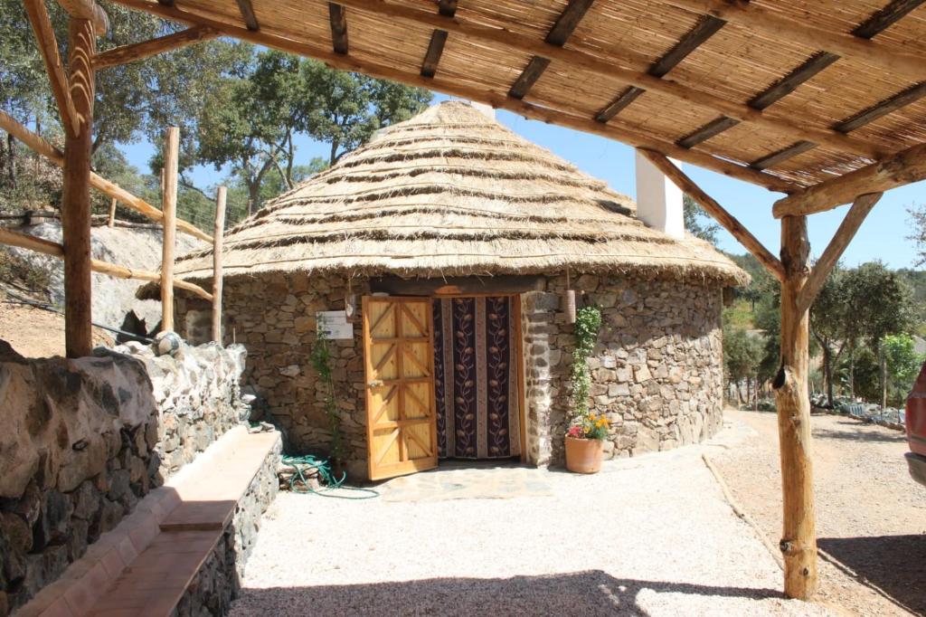 una pequeña casa de piedra con techo de paja en Alojamiento Los Chozos, en Cazalla de la Sierra