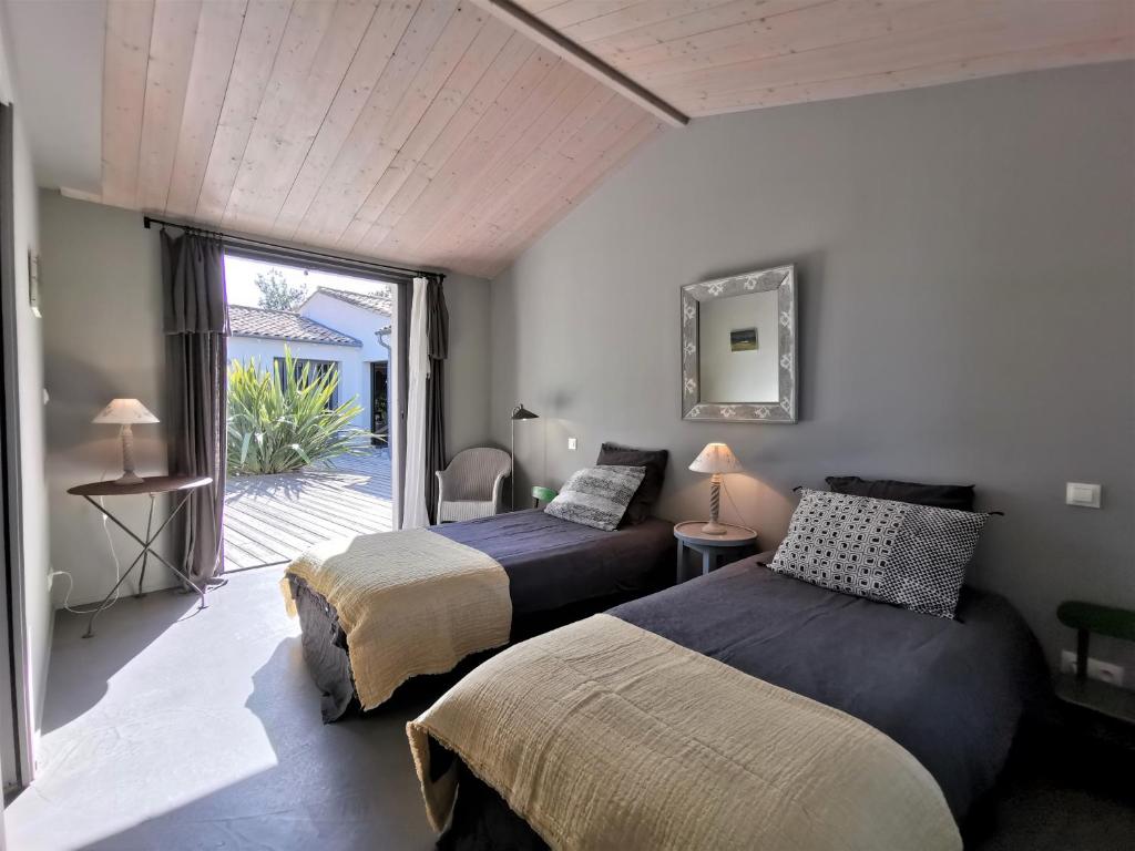 a bedroom with two beds and a door to a patio at Derrière la plage : suite, patio et pergola in Le Bois-Plage-en-Ré