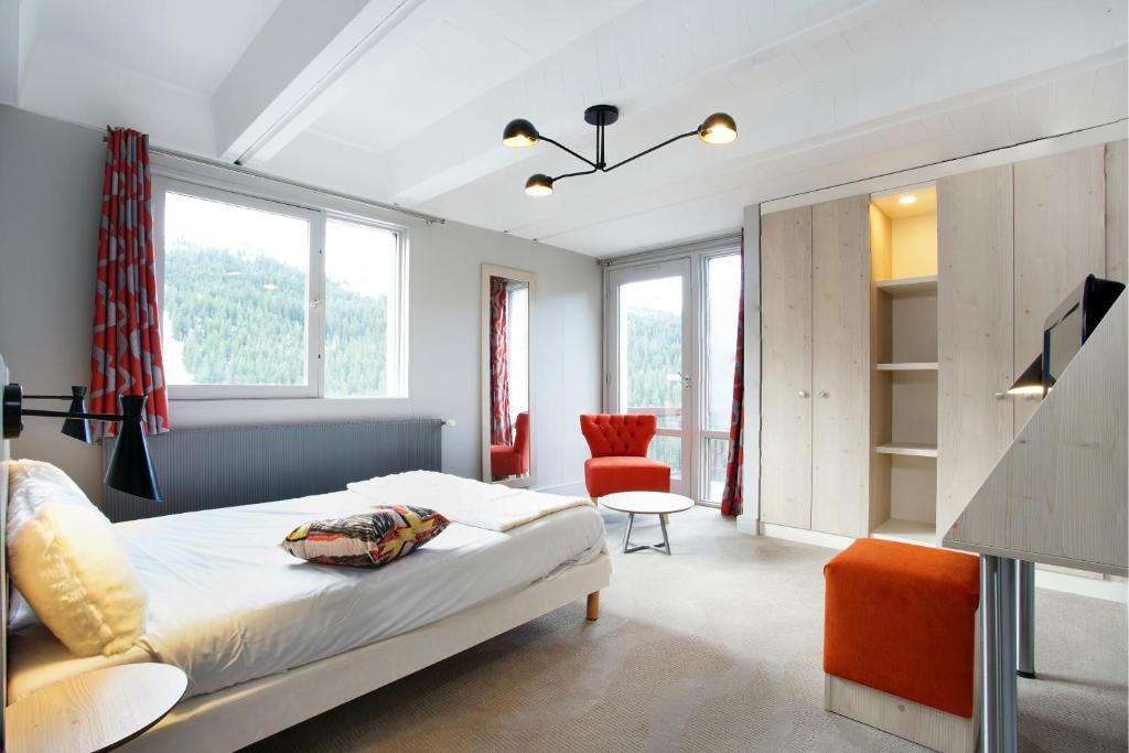 a bedroom with a bed and a chair and windows at Hôtel Club mmv Le Flaine *** in Flaine