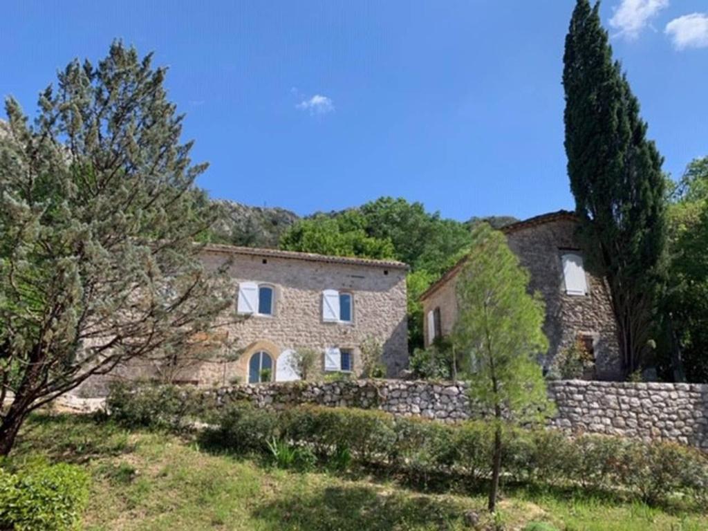 a stone house with a stone wall and trees at Magnifique Mas Cevenol in Anduze