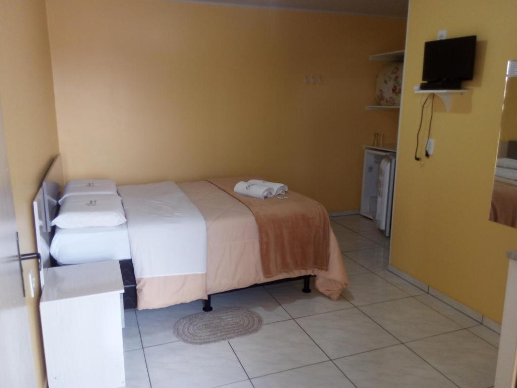 Un dormitorio con una cama y un televisor en una pared. en Pousada Campanário, en Cambará