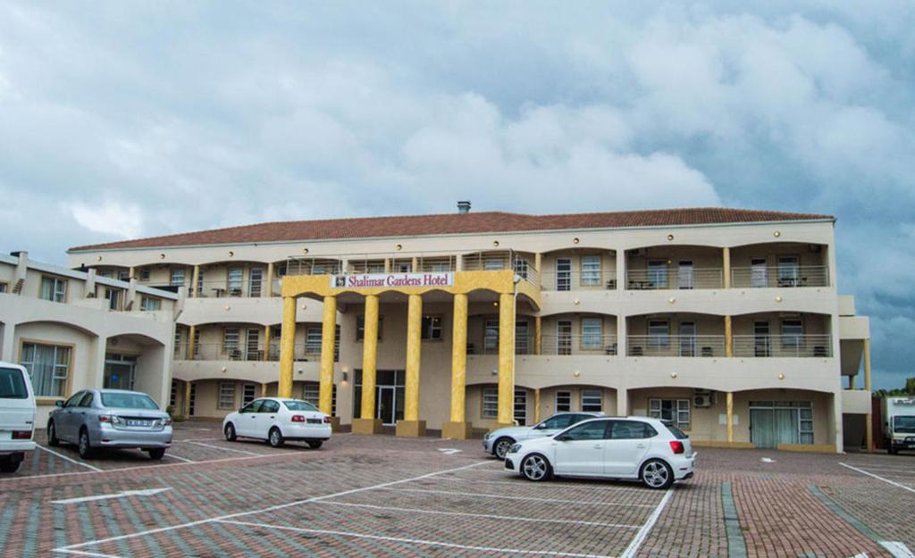 un grand bâtiment avec des voitures garées dans un parking dans l'établissement SHALIMAR GARDENS HOTEL, au Cap