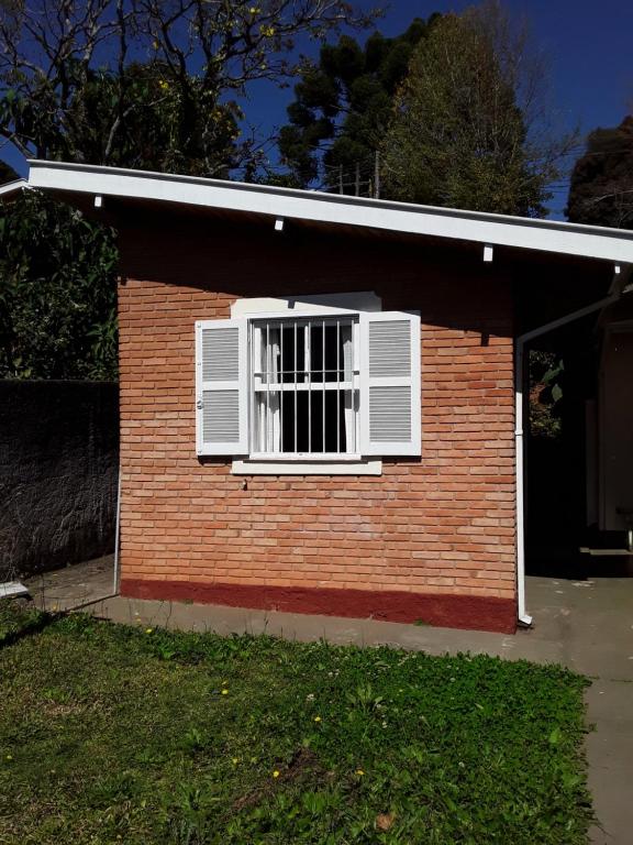 una pequeña casa de ladrillo con una ventana en ella en Suíte bem localizada. en Campos do Jordão