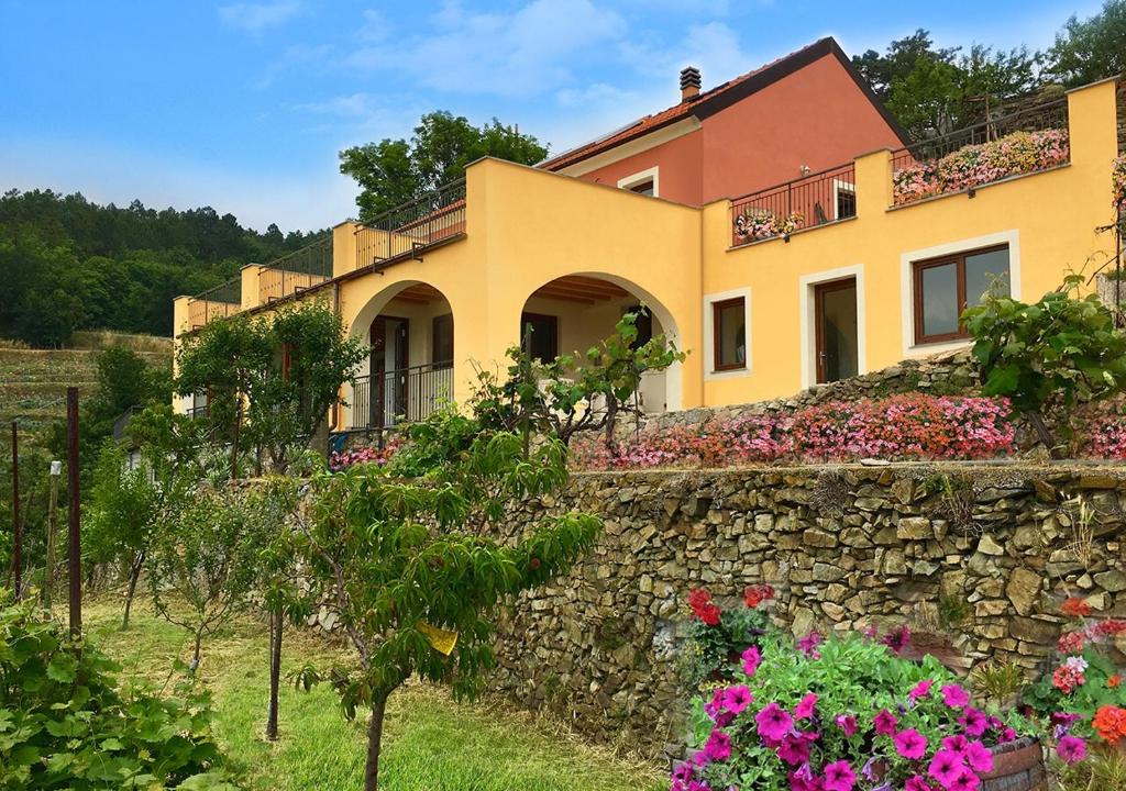 uma casa em cima de uma parede de pedra com flores em Agriturismo LaValleggia em Tovo San Giacomo