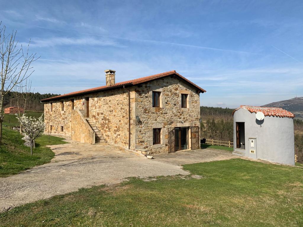 ein altes Steinhaus mit einem Weg dorthin in der Unterkunft El manantial in Liérganes