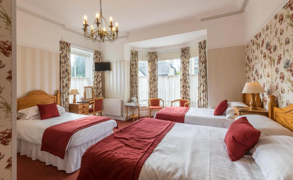 a hotel room with two beds and a chandelier at Dorchester House in Keswick