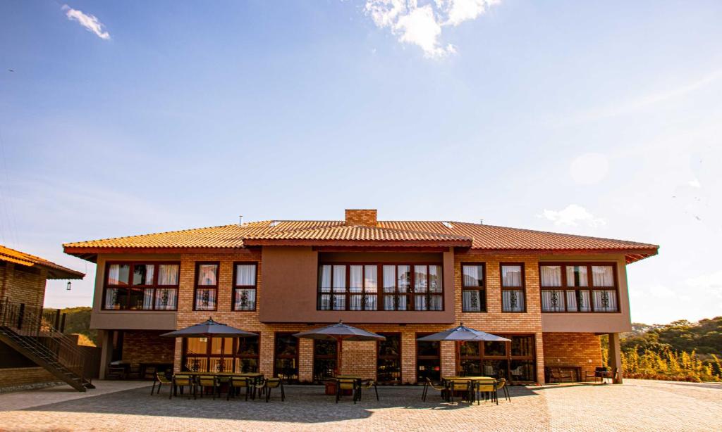 a building with tables and umbrellas in front of it at Hotel Vinícola Davo in Ribeirão Branco