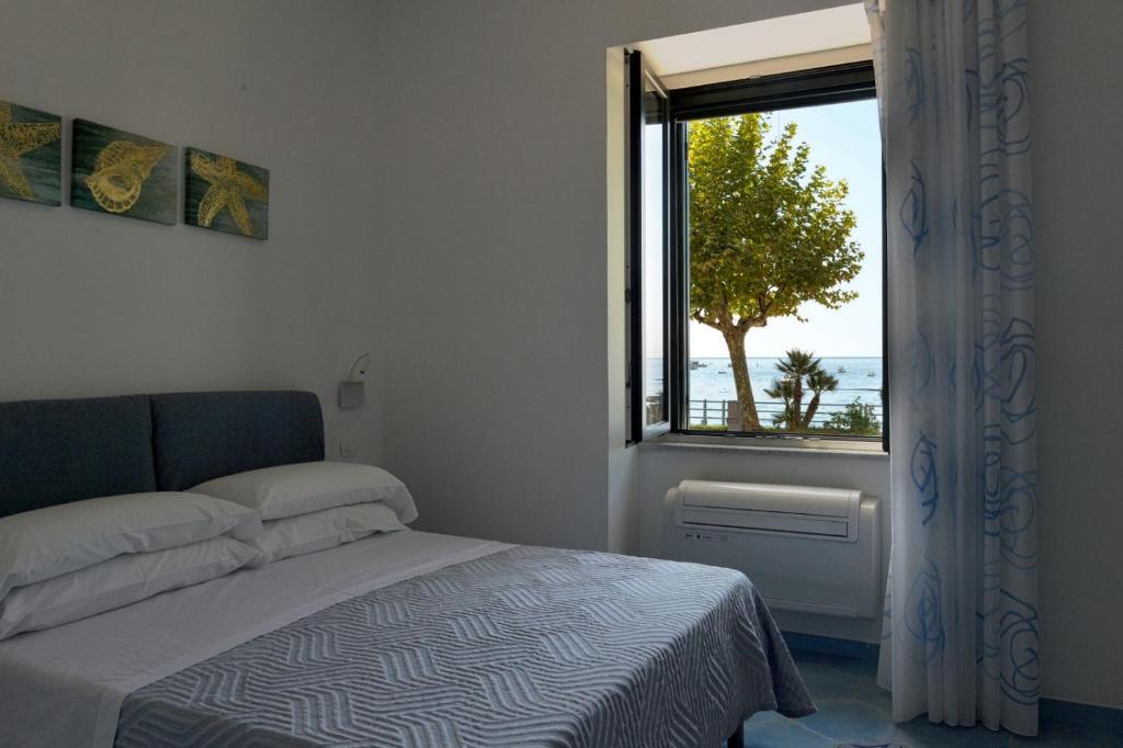 a bedroom with a bed and a window with a tree at Una Finestra sul Mare in Maiori