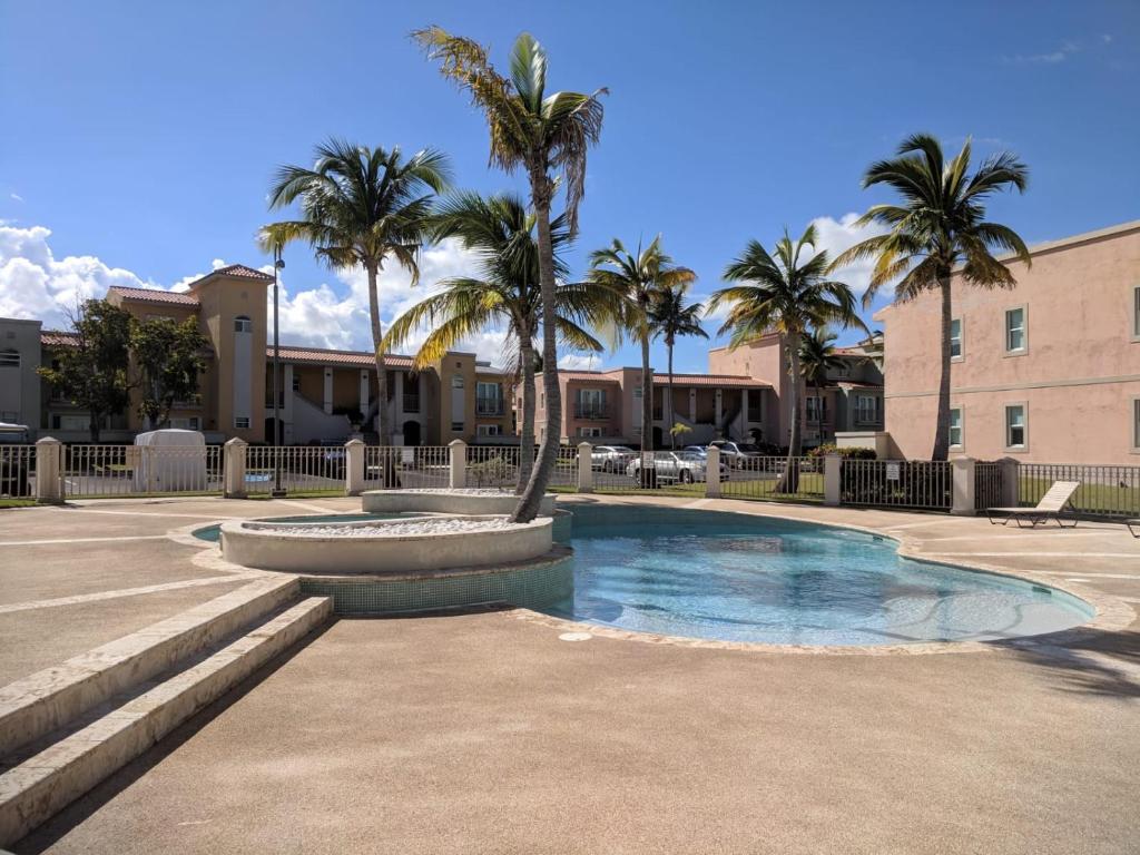 a swimming pool with a fountain in a courtyard with palm trees at Mariposa Beach House in Humacao