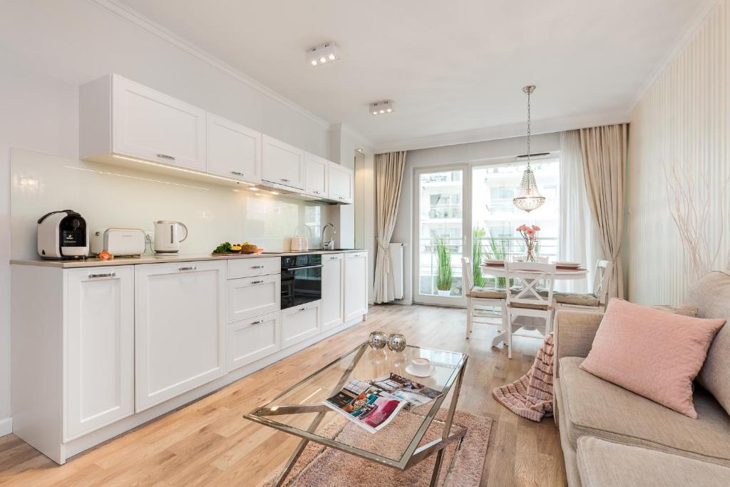 a kitchen and living room with a couch and a table at Apartamenty Black&White - Silver House in Gdynia