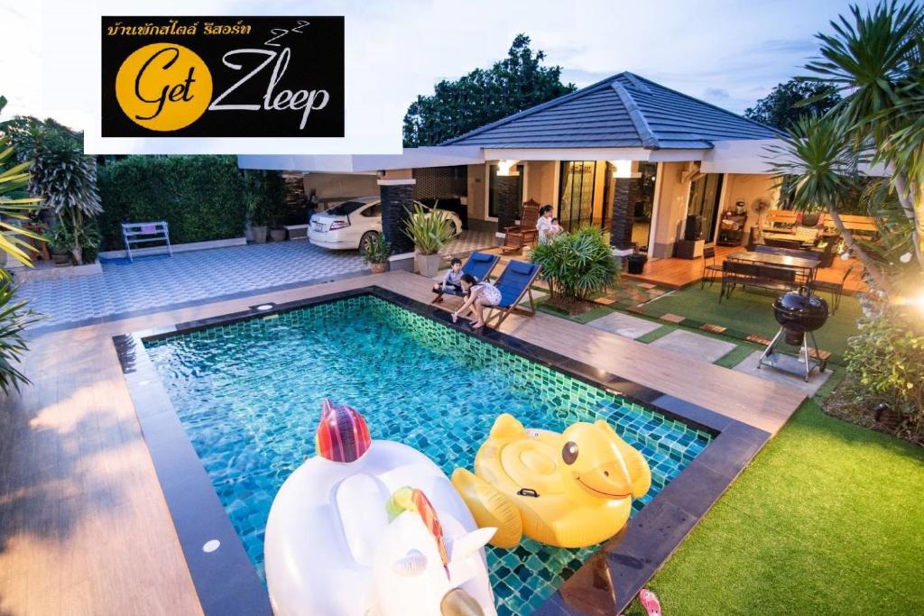 a swimming pool with two inflatable swans in a backyard at GetZleep House Sattahip in Sattahip