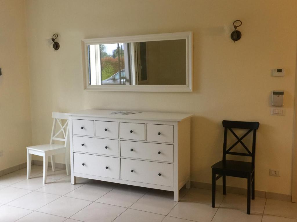una camera da letto con cassettiera bianca e specchio di Casa vacanza a Castelfranco Emilia