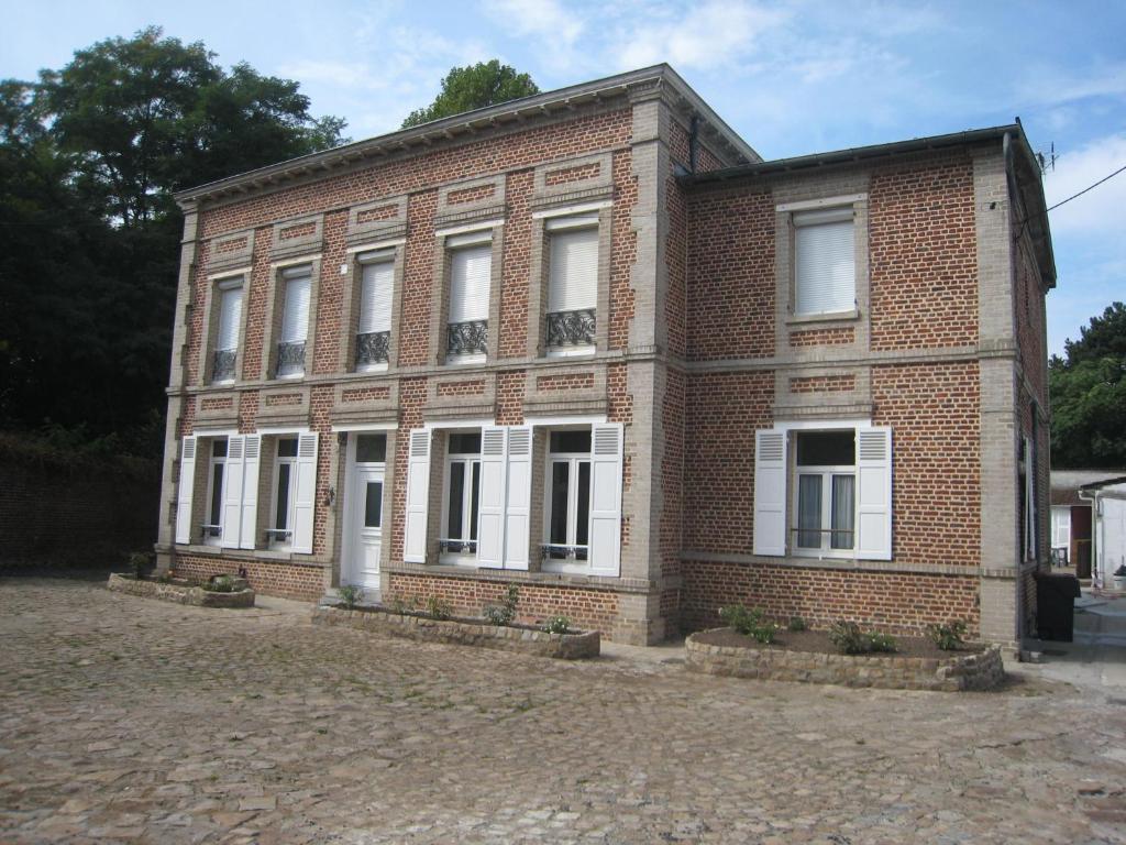 an old brick building with white windows on a street at La KEFOISE in Fouquières-lès-Lens