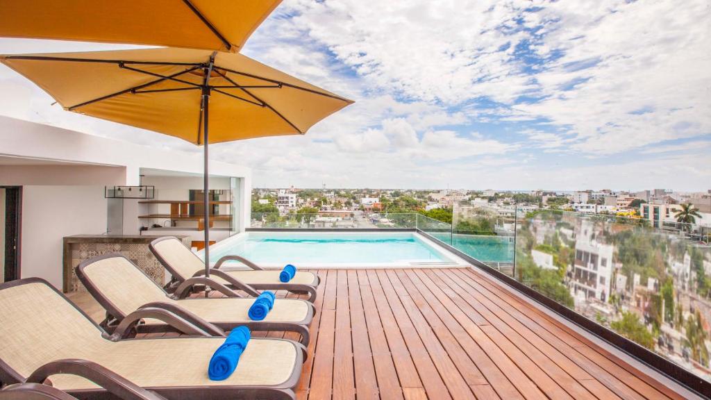 una terraza con sillas, una piscina y una sombrilla en Hotelito del Mar Playa del Carmen en Playa del Carmen