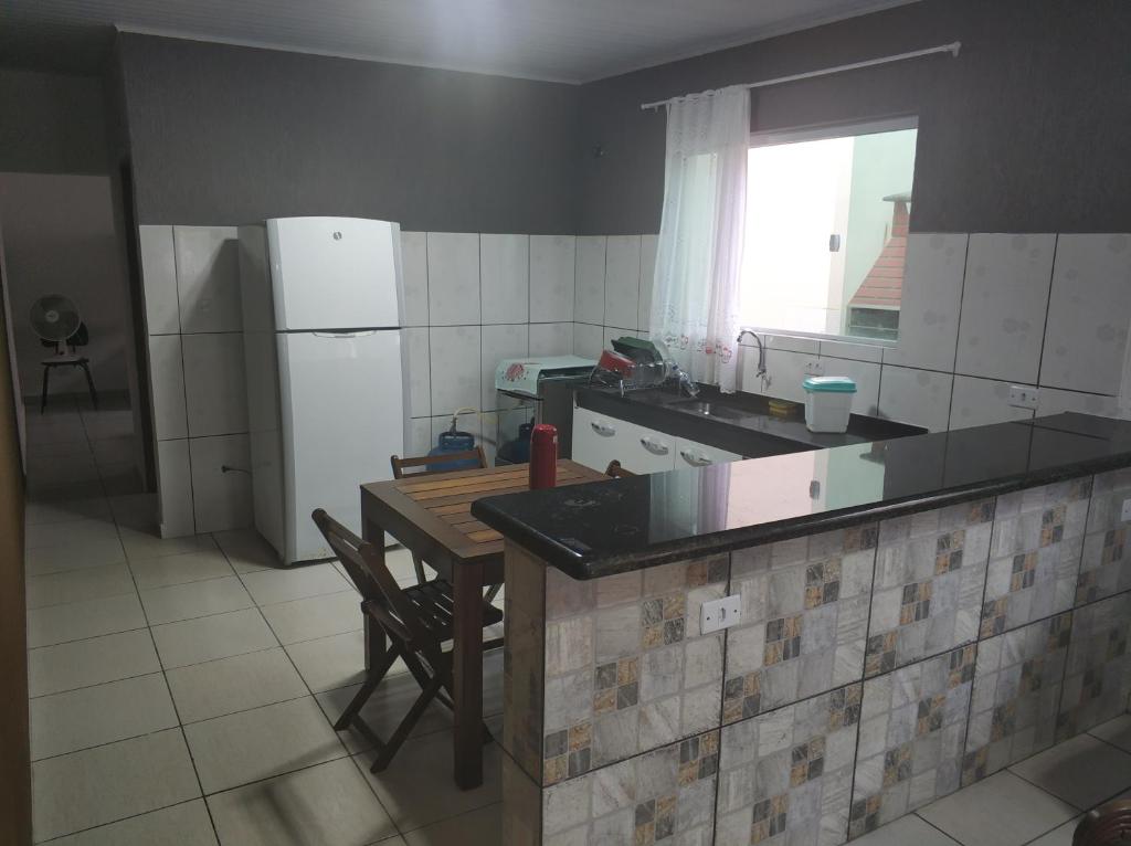 a kitchen with a table and a refrigerator at CASA TERREA PERUIBE 5 MIN DO CENTRO,LINDA VISTA, PRÓXIMO A TUDO. in Peruíbe