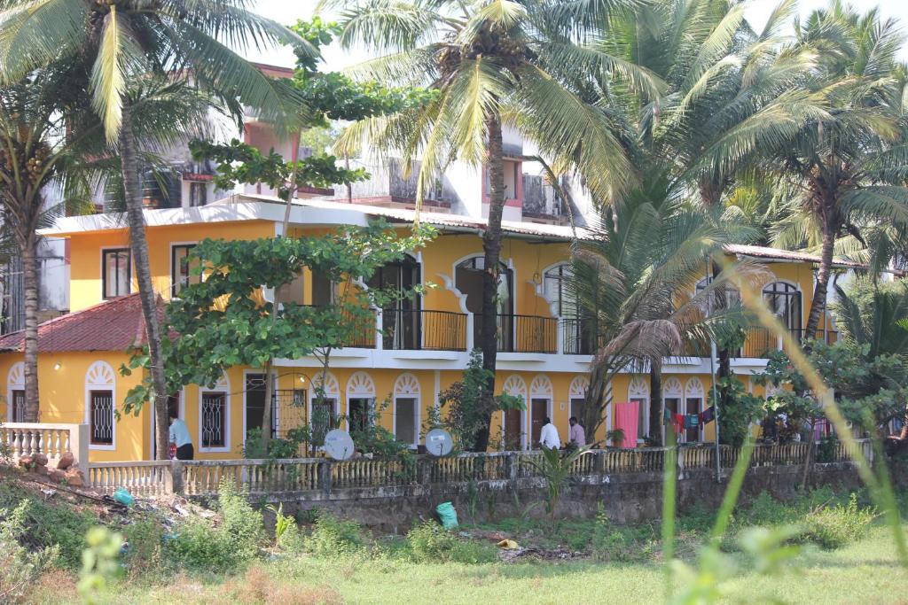 a yellow house with palm trees in front of it at Country View Cottage Colva in Colva