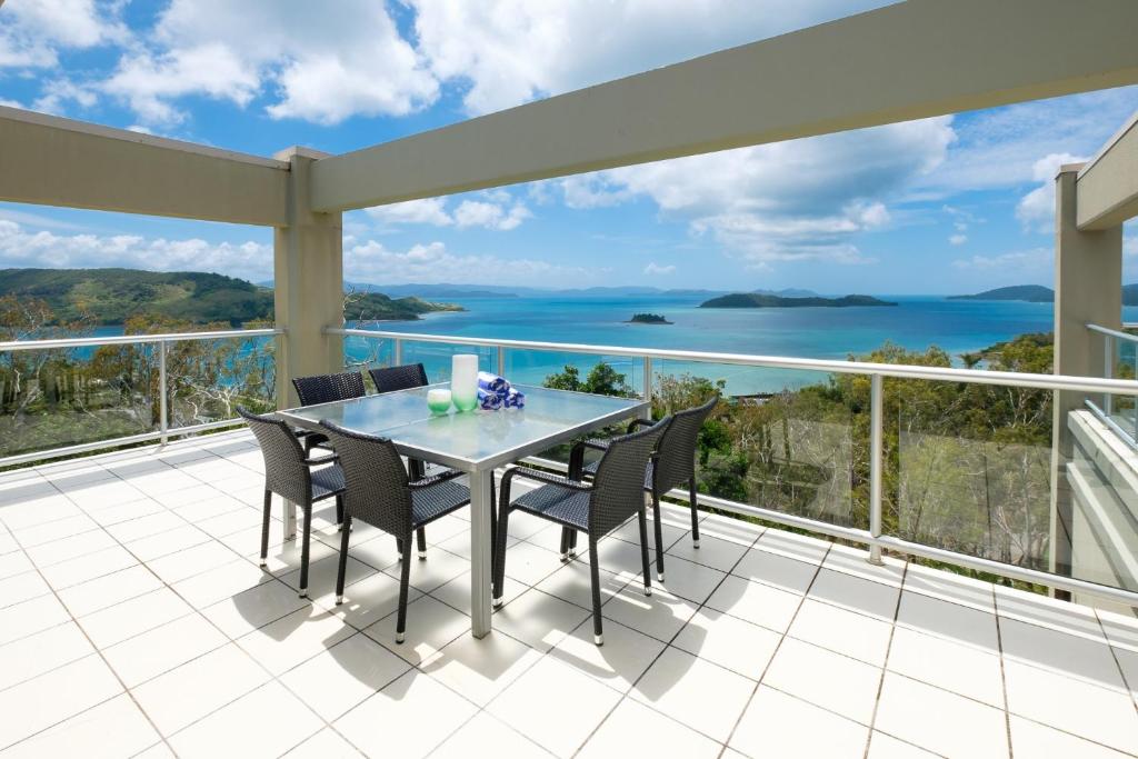 a balcony with a table and chairs and a view of the ocean at Ocean Sunsets - Skiathos in Hamilton Island
